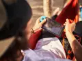 Osoba w hamaku gra na Nintendo Switch. Czas ładowania konsoli jest krótki, więc można grać wszędzie.