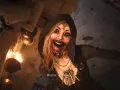 Przerażająca postać z Resident Evil Village, otoczona przez muchy, z krwią na ustach. Czas gry wciąga w mroczny świat.