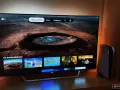 Telewizor z interfejsem Apple TV i konsola PS5 obok. Na ekranie widać menu z filmami i serialami, np. "Ogniste Kule" i "Moja Ewolucja".