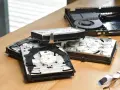 Rozłożone wnętrze konsoli PS4 Slim, widać dysk i mechanizm napędu. Komponenty leżą na drewnianym blacie, przypominając o kompaktowych ps4 slim wymiary.