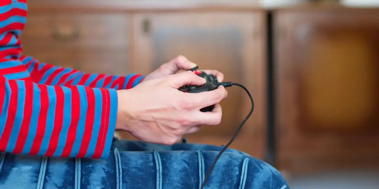 Ręce trzymające kontroler, gotowe do gry. Dowiedz się, jak podłączyć pada od Nintendo Switch do PC, by cieszyć się grami na większym ekranie.