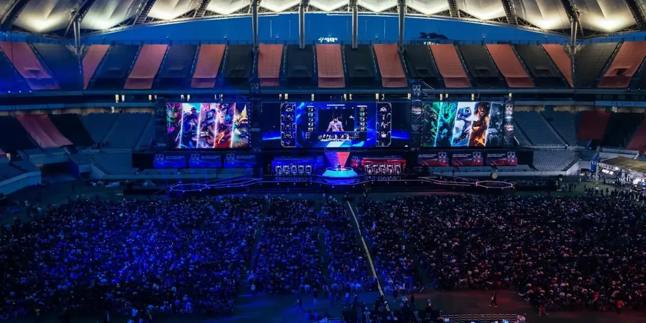 Wielki stadion wypełniony fanami oglądającymi transmisję z gry League of Legends. Na ekranach widać postacie i graczy, a tłum reaguje na emocjonujące rangi w lolu.
