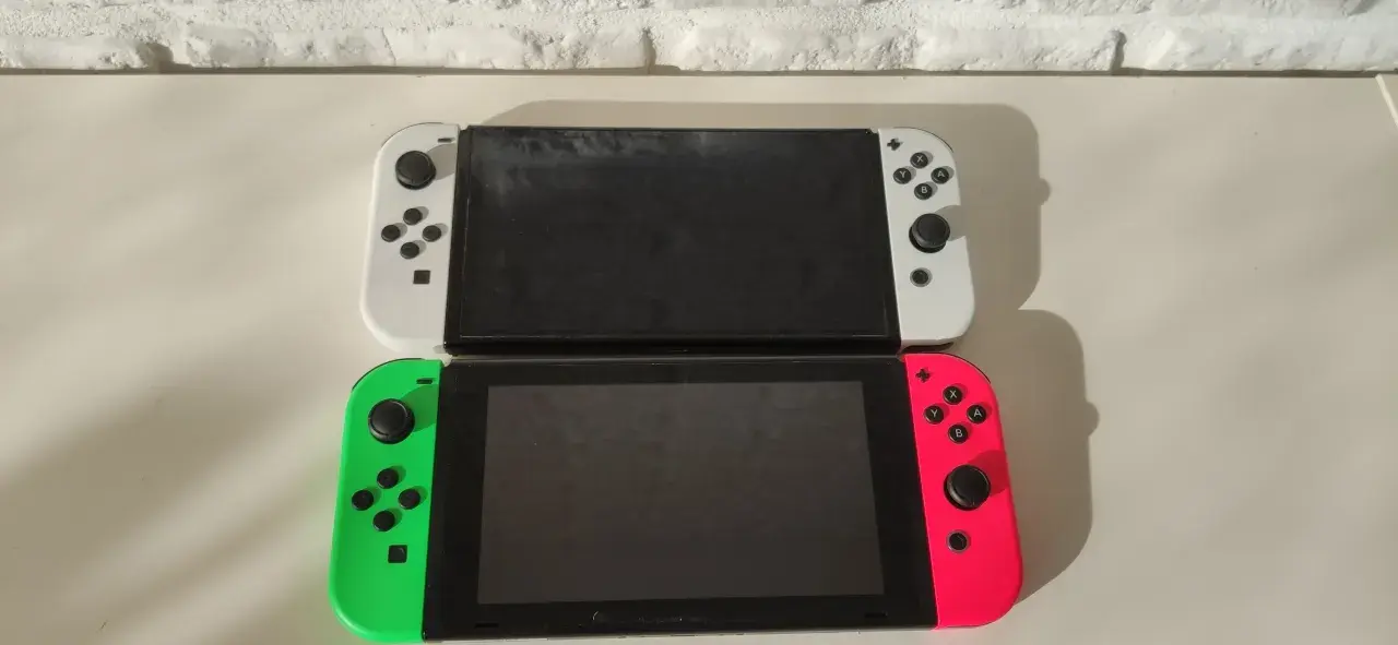 Dwa konsole Nintendo Switch OLED, biała i neonowo-różowa z zielonym Joy-Conem, gotowe na premierę.
