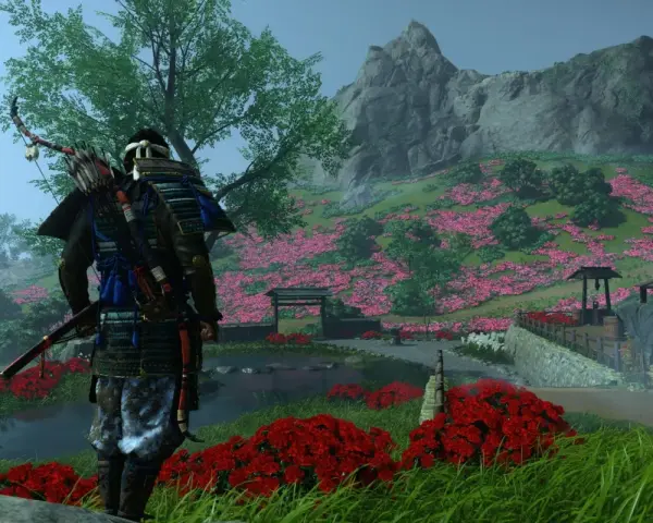 Samuraj w zbroi z łukiem na plecach stoi na tle kwitnącej wiśni. Sceneria z gry Ghost of Tsushima na Xbox.