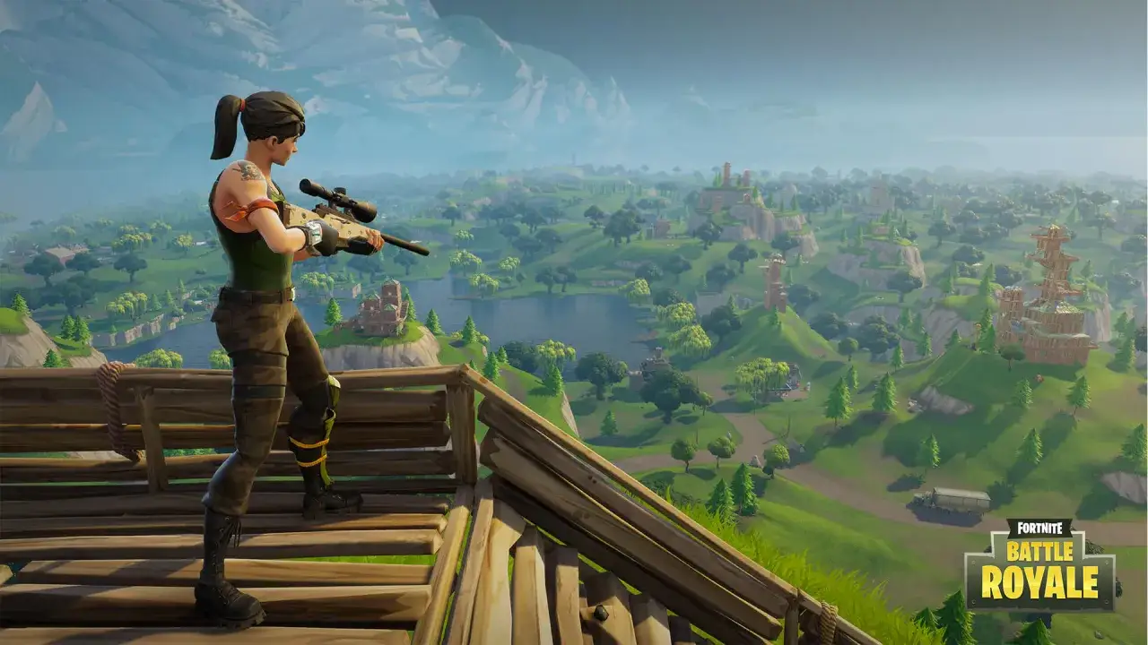 Postać z karabinem snajperskim na drewnianej platformie, obserwująca krajobraz wyspy. Gra Fortnite, która niedługo będzie obchodzić kolejne urodziny, wciąż zachwyca.